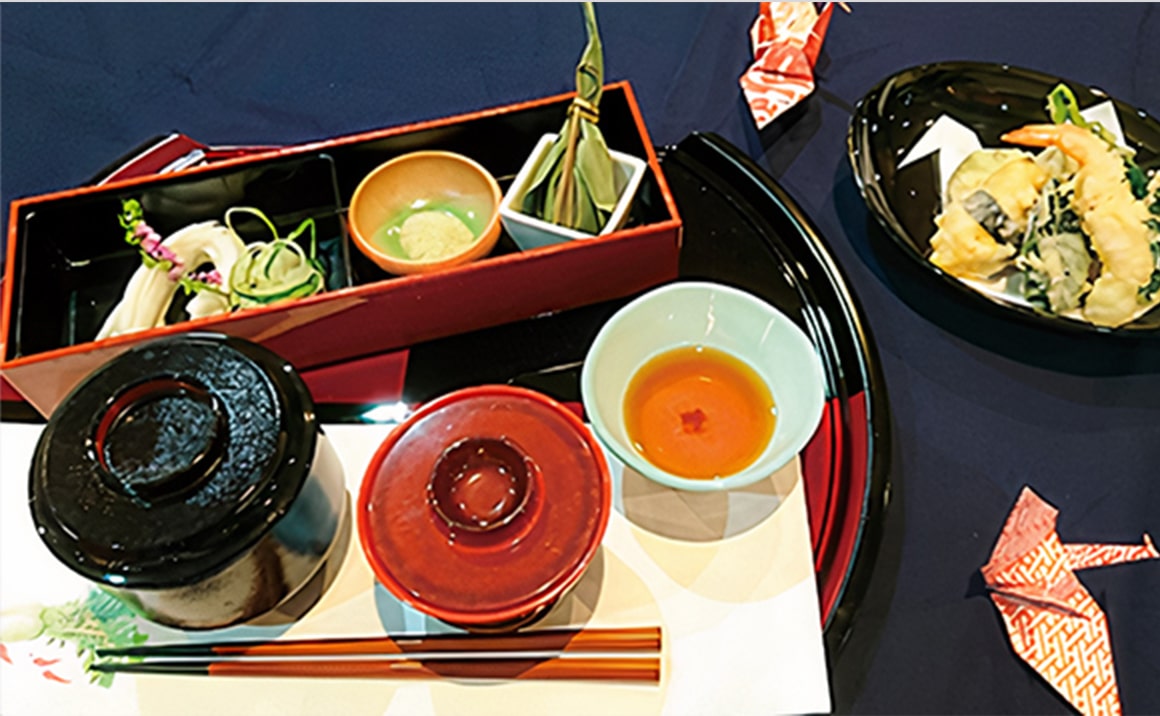 懐石料理のセッティング。朱塗りの重箱、汁椀、小皿が配置された日本式の食事風景。