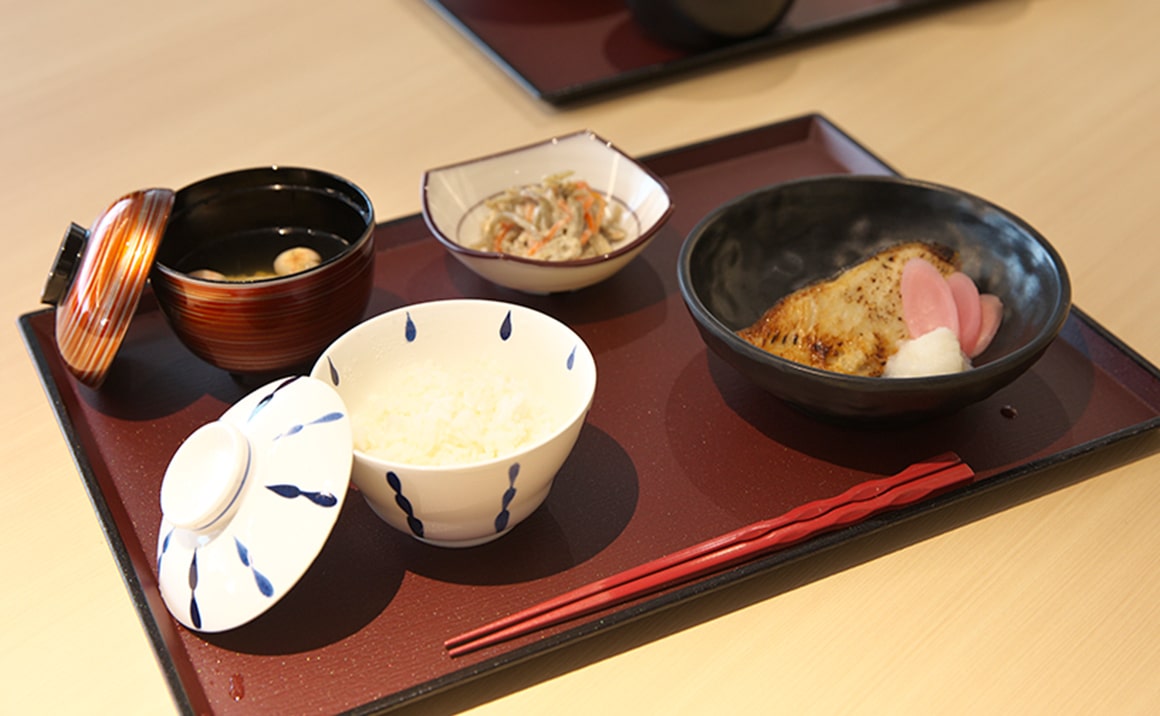 介護施設の食事。白飯、汁物、おかず、副菜がセットされた配膳風景。
